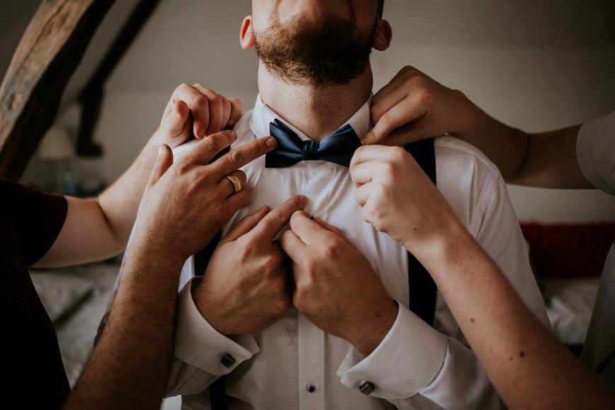 le futur marié le matin du mariage, habillage de monsieur (chemise, noeud papillon) aidé par les garçons d'honneur