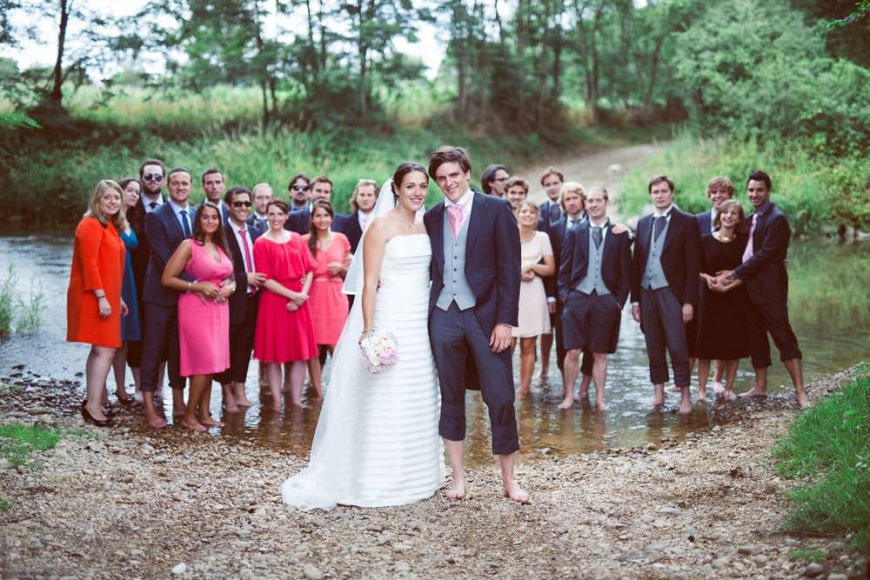 Une photo de groupe les pieds dans l'eau où les mariés et leur invités profitent de la rivière pour se rafraichir !