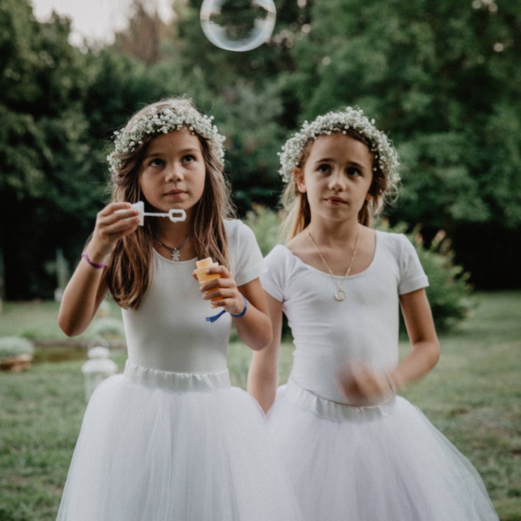 Les enfants - Voici deux jolies petites filles, couronnes de fleurs dans les cheveux, qui font de belles bulles de savons ! Photo ©Joël Assuied. Trouvez le <a href=
